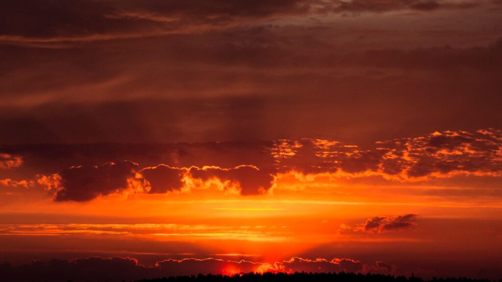 Captivating orange sunset with dramatic clouds and warm atmosphere.